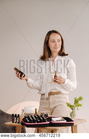 A Girl With A White Blouse Holds Bottles Of Essential Oils In Her Hands