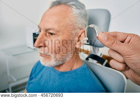 Close-up Of Hearing Aid Near Senior Male Patients Ear At Audiology Clinic. Hearing Solutions, Hearin