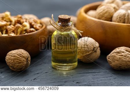 Glass Bottle With Essence, Raw Walnut Peeled And In Their Shells, Rustic Style, Selective Focus