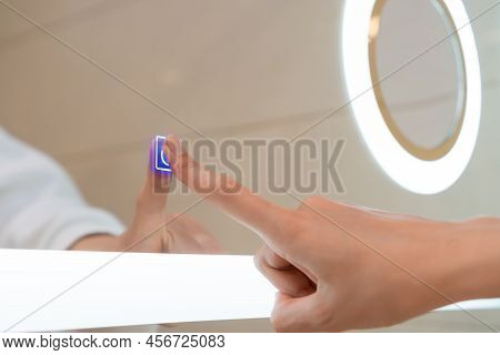 Woman's Hand Turns On The Illumination Of The Bathroom Mirror By Touching The Touch Button On And Of