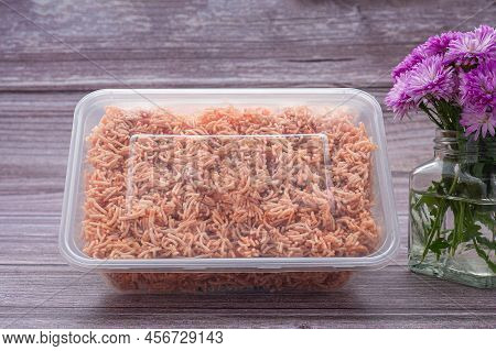 A Box Of Sweet And Sour Crispy Noodles (or Mee Krob In The Thai Language) With A Vase Of Purple Flow