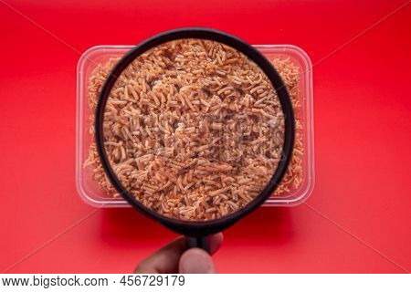 Hand Holding A Magnifying Glass Looking At A Box Of Sweet And Sour Crispy Noodles Or Mee Krob In The