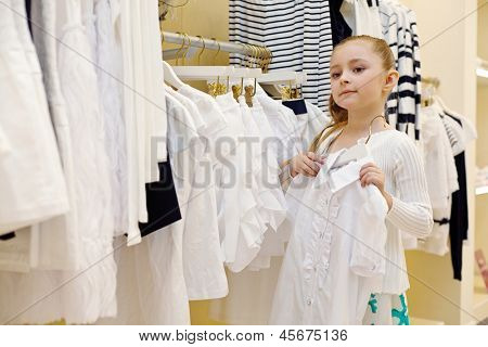 Bambina cerca su camicetta bianca nel negozio di abbigliamento