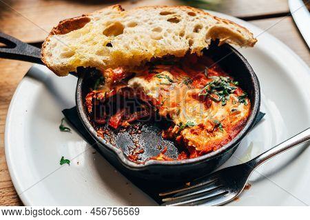Half Eaten Freshly Made Shakshuka With Tomato, Red Pepper, Feta, Egg, Coriander And Pieces Of Homema