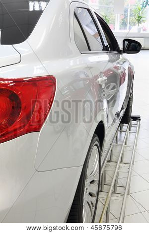 Een back-rode lichten van nieuwe witte glanzende auto in Bureau van winkel verkopen van auto's staan.