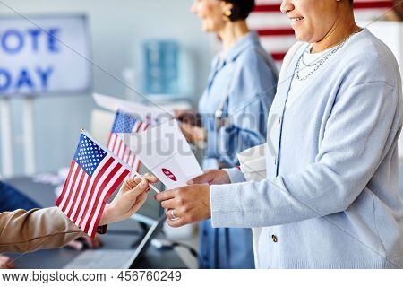 Closeup Of Smiling Woman Taking Voting Ballot On Election Day With American Flag, Copy Space