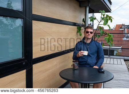 40 Year Old White Man With Sungasses, Drinking Coffee On The Terrace Of His Apartment, Brussels, Bel