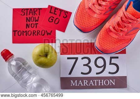 Flat Lay Marathon Accessories On White Background. Red Shoes With Green Apple And Bottle Of Water.