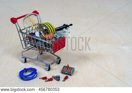 A Shopping Cart With Electrical Parts And Components. Terminals, Light Bulb, Electrical Tape, Cable 