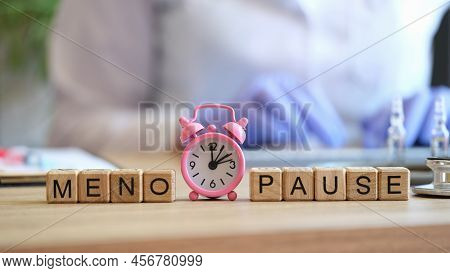 Close-up Of Word Menopause Collected Of Wooden Cubes In Raw And Pink Alarm-clock. Gynecology, Women 