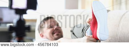 Close-up Of Middle Aged Male Putting On Trendy Red Sneaker Showing On Camera. Try On New Model Of Co