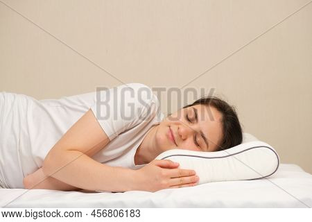 A Woman Sleeps On An Orthopedic Pillow Made Of Memory Foam, Lying On A Bed. The Correct Pillow For A