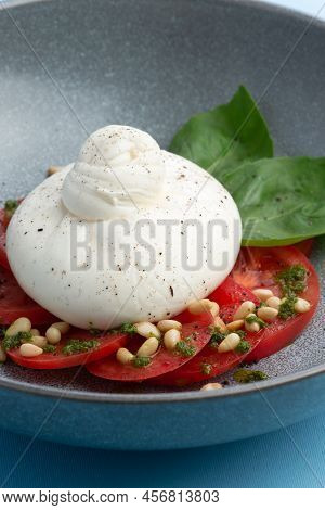 Buratta Cheese And Tomatoes In A Bowl. Decorated With Pine Nuts. Selective Focus.