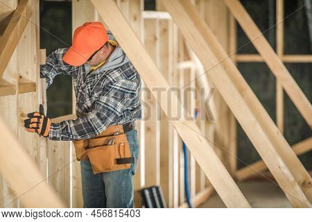 Constructing The Frame Of The Wooden Building. Professional Construction Worker Fitting The Wooden E