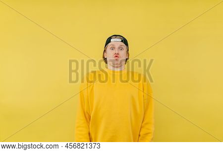 Shocked Funny Guy In Yellow Clothes Looks At The Camera With A Crazy Face, Isolated On A Yellow Back