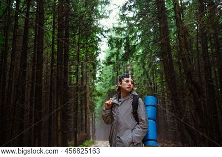 Portrait Of A Male Tourist In The Rain With A Backpack And In Casual Clothes On A Background Of Coni