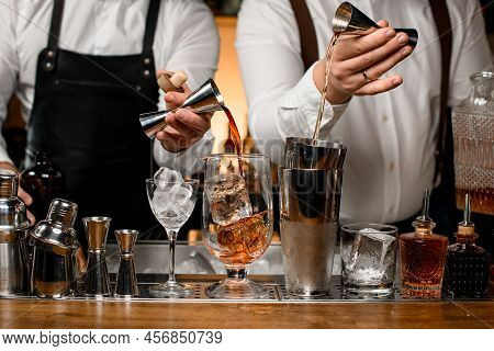 Great View On Mixing Cup With Ice And Shaker Cups On The Bar Counter Into Which The Bartenders Pour 