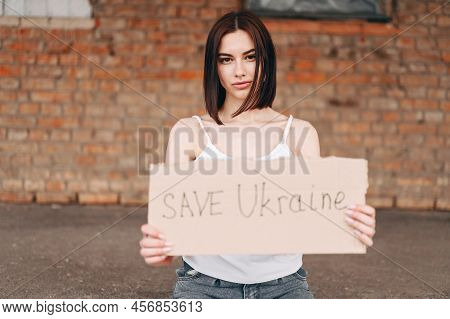 Out Of Focus Horizontal Woman Portrait With Poster Save Ukraine In Out Of Focus. A Woman With A Bell