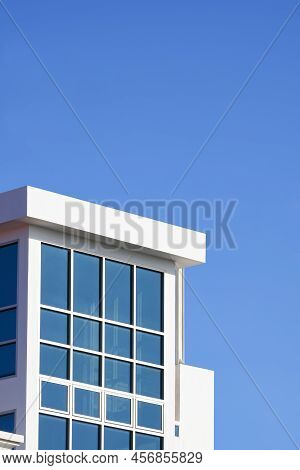 External View Of Glass Wall Of White Modern Deckhouse Against Blue Clear Sky Background In Vertical 