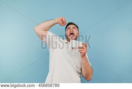 Portrait Of A Joyful Bearded Man With A Smartphone In His Hand Emotionally Rejoices And Shouts From 