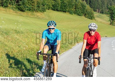 Cyclists Couple On The Road In Summer Cycling Gear Pedaling And Gliding Positions On Racing Cycles.