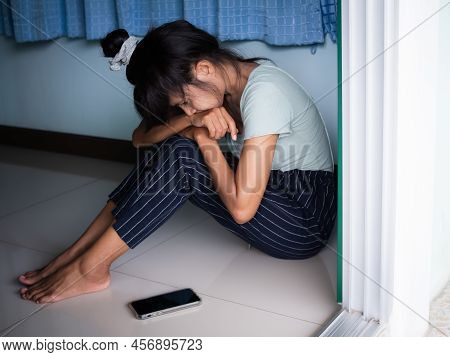 Broken Heart Concept. Alone Woman Sitting And Looking Mobile Fone At Room. She Sad, Cry, Stress And 
