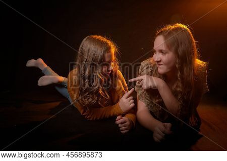 Two Cheerful Joyfull Sisters Having Fun Together In Dark Studio With Black Background