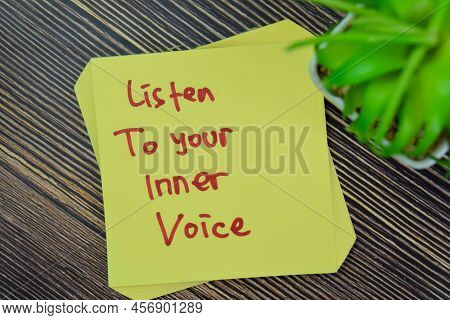 Concept Of Listen To Your Inner Voice Write On Sticky Notes Isolated On Wooden Table.