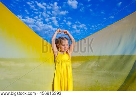 Ukrainian Girl 7 Years Old, She Is A Patriot Of Ukraine, Dressed In A Yellow Dress Against A Blue Sk