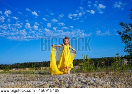 Ukrainian Girl 7 Years Old, She Is A Patriot Of Ukraine, Dressed In A Yellow Dress Against A Blue Sk