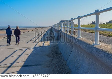 Prestatyn, Uk. Mar 27, 2022. A Couple Enjoy A Walk Along The Promenade At Barkby Beach On A Sunny Sp