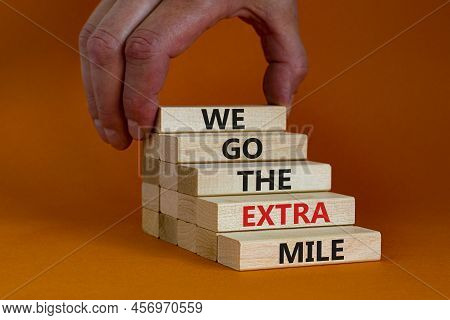 We Go The Extra Mile Symbol. Wooden Blocks With Words We Go The Extra Mile. Beautiful Orange Backgro