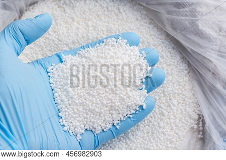 Closeup Photo Of A Hand In Blue Glove Holds White Fertilizer For Plants. Big Bag With Chemical Npk F