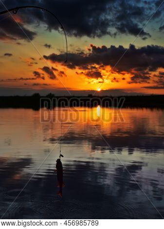 Fishing At Sunset. Catching Predatory Fish On Spinning. Sunset Colors On The Water Surface, Sunny Pa