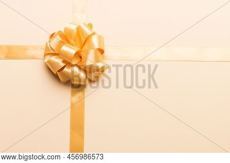 Top View Of Gold Ribbon Rolled And Yellowbow Isolated On Colored Background. Flat Lay With Copy Spac