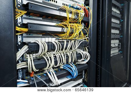 technology equipment with optical fibre cables connected to rack servers in room