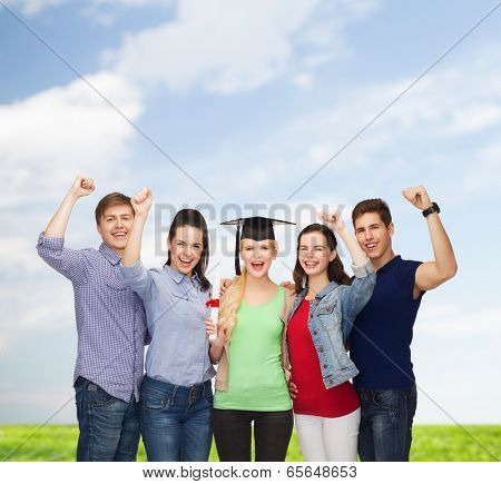 education and people concept - group of standing smiling students with diploma and corner-cap