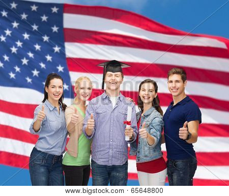 education and people concept - group of standing smiling students with diploma and corner-cap showing thumbs up