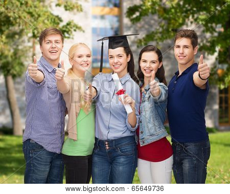 education and people concept - group of standing smiling students with diploma and corner-cap showing thumbs up