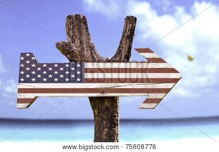 USA wooden sign with a beach on background 
