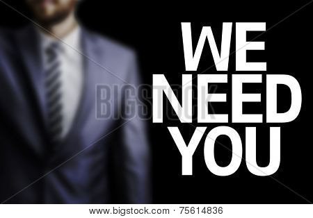 We Need You written on a board with a business man on background