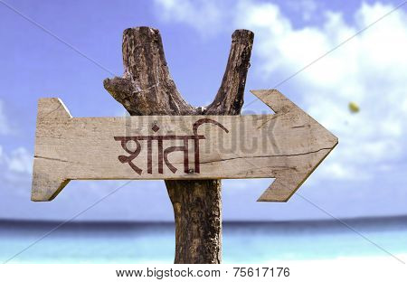 Peace (In Hindi) wooden sign with a beach on background