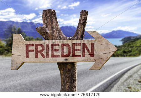 Peace (In German) wooden sign with a road background