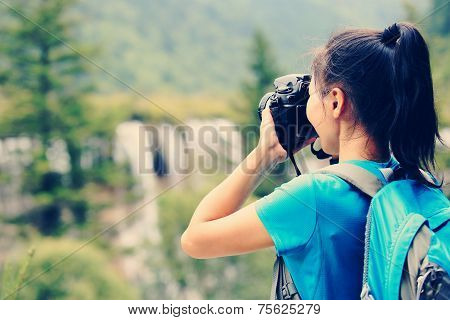 woman tourist/photographe taking photo with digital camera in jiuzhaigou national park,china