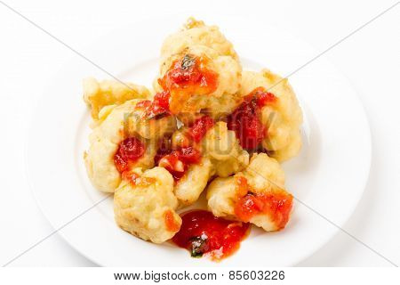 Florets of cauliflower parboiled then dipped in batter and deep fried with tomato sauce from above