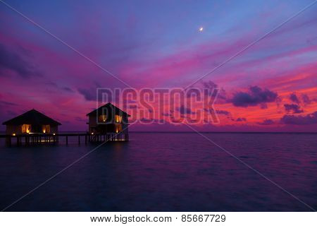 Sunset in the Maldives with a view of the lagoon, beach and bungalows