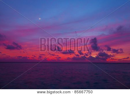 Sunset in the Maldives with a view of the lagoon, beach and bungalows