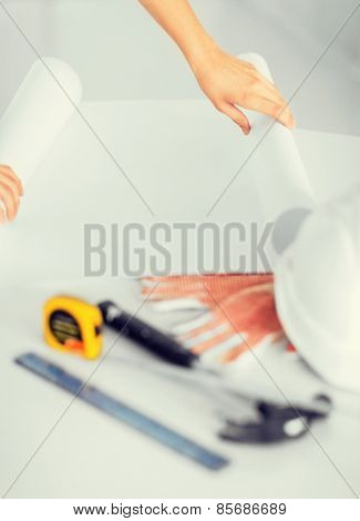architecture and home renovation concept - architect with blank blueprint, flexible ruller and helmet