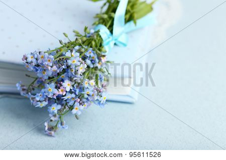 Forget-me-nots flowers on book, on blue background