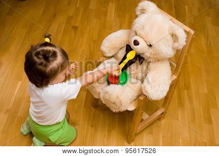 Little Girl Playing With A Toy Bear And Tea Things
